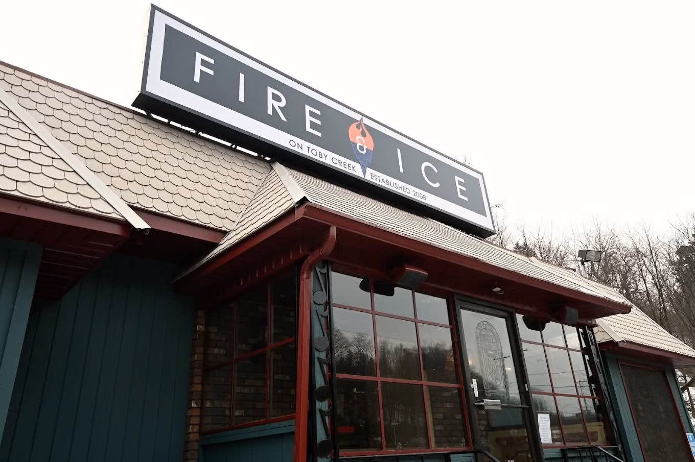 Exterior view of a building with a large FIRE ICE restaurant sign on the roof edge, above red-framed glass windows